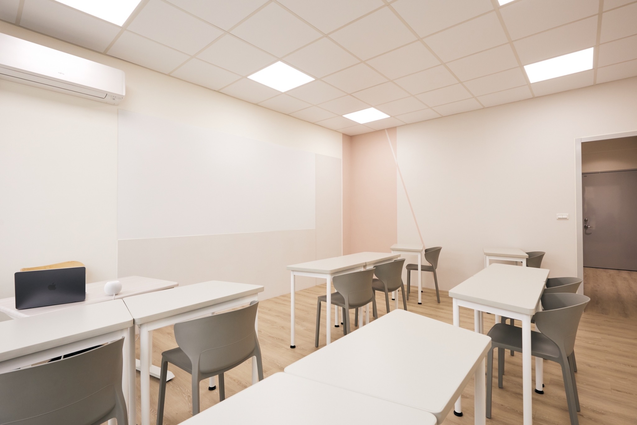 Bright Enfluence classroom with white desks and grey chairs